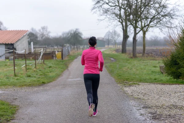 Vista trasera de una joven en forma corriendo — Foto de Stock