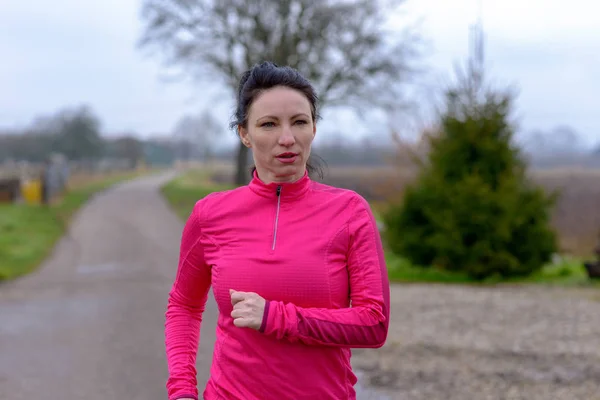 Mujer decidida corriendo a lo largo de un camino rural — Foto de Stock