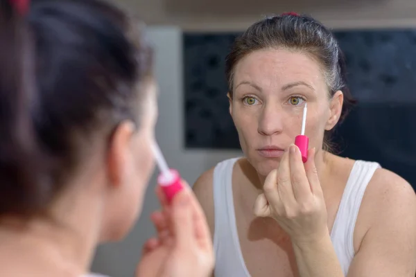 Mujer aplicando un brillo de labios pastel moderno — Foto de Stock