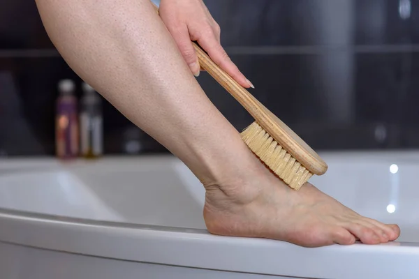 Frau schrubbt ihr Bein mit einer Bürste — Stockfoto