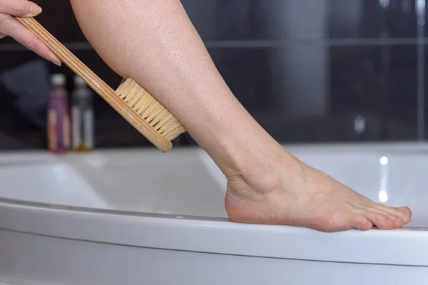 Mujer fregando su pierna con un cepillo — Foto de Stock