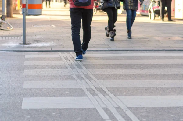 Menschen überqueren einen Zebrastreifen in einer Straße — Stockfoto