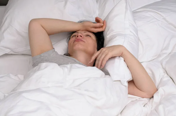 Young woman sleeping on her back in bed