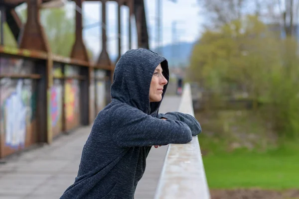 Mujer seria y reflexiva de pie en un viejo puente — Foto de Stock