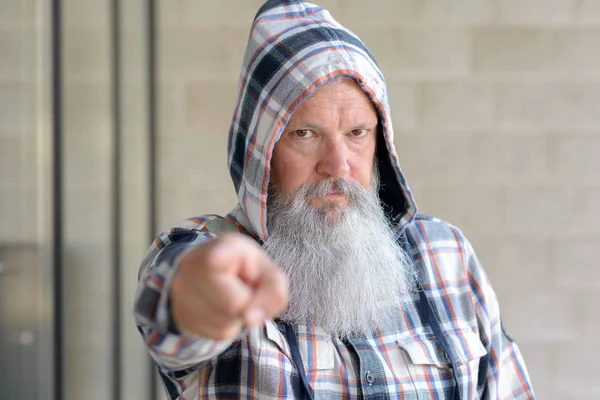 Stern man wearing a hooded top pointing with his finger with focus to his face