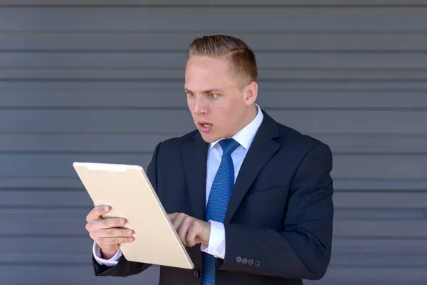 Joven hombre de negocios mirando horrorizado a su tablet-pc — Foto de Stock