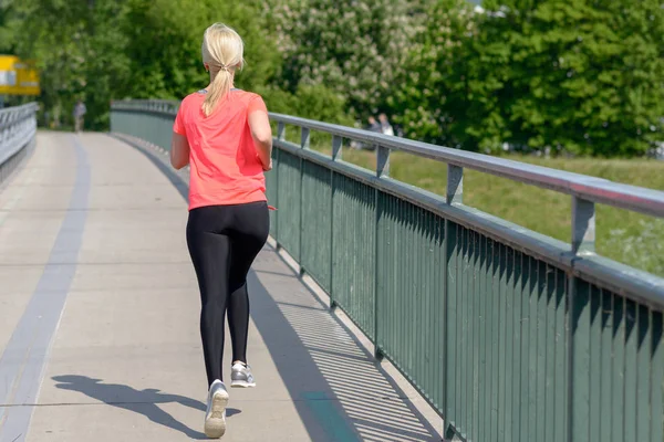Blond woman jogging away from the camera