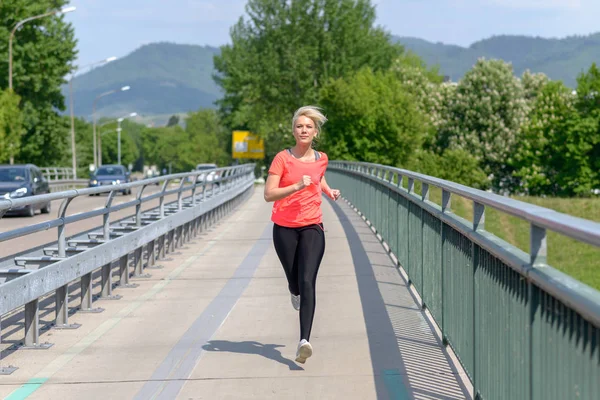 Ajuste mujer joven sana corriendo a través de un puente — Foto de Stock