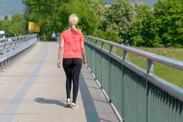 Mujer rubia corriendo a través de un puente peatonal — Foto de Stock