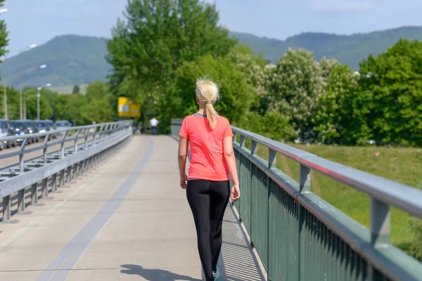 Mujer rubia corriendo a través de un puente peatonal — Foto de Stock