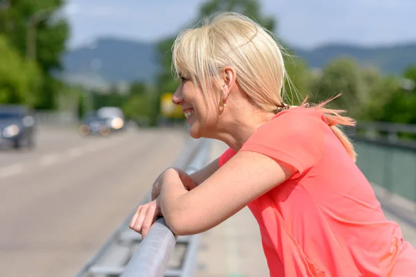 Mujer feliz riéndose mientras se para en un puente — Foto de Stock