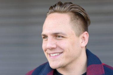 Yakışıklı genç adam bir gülümsemeyle yana bakıyor.