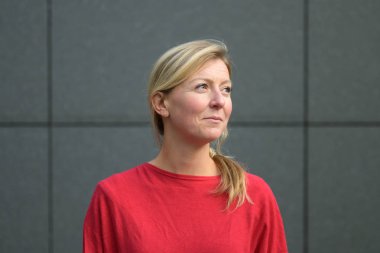 Çekici sarışın kadın gülümseyerek yana bakıyor.