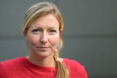 Ciddi bir kadın kameraya dikkatlice bakıyor.