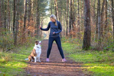 Sportive woman training her dog to sit