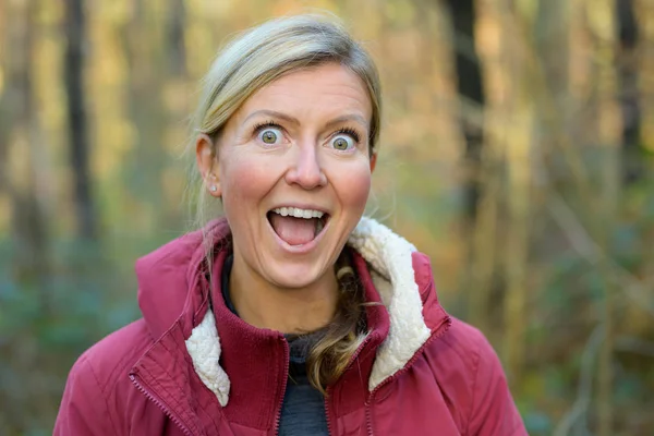 Blond woman in red jacket showing funny grimace — Stock Photo, Image