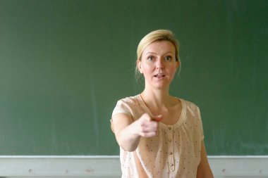 Okul öğretmeni parmağıyla işaret ediyor.