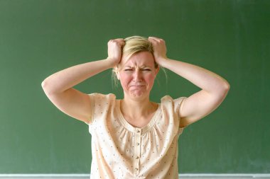 Öfkeli okul öğretmeni saçlarını yoluyor.