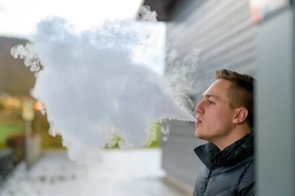 Jeune homme fumant une cigarette électronique à l'extérieur — Photo