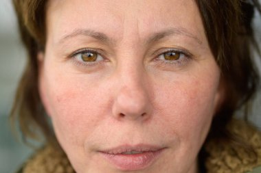 Ciddi orta yaşlı İspanyol kadın kameraya bakıyor. Hafif somurtkan ve düşünceli bir ifadeyle yakın çekimde.