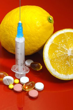 Limon ve şırınga kırmızı bir arka plan üzerinde. Vitamin ilaçları karşı. C vitamini.