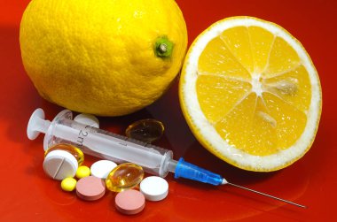 Limon ve şırınga kırmızı bir arka plan üzerinde. Vitamin ilaçları karşı. C vitamini.