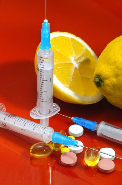 Limon ve şırınga kırmızı bir arka plan üzerinde. Vitamin ilaçları karşı. C vitamini.
