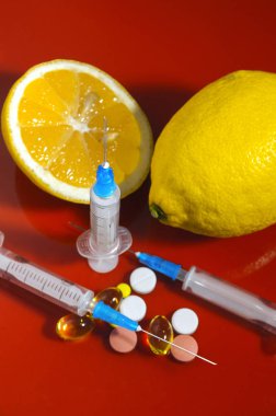 Limon ve şırınga kırmızı bir arka plan üzerinde. Vitamin ilaçları karşı. C vitamini.