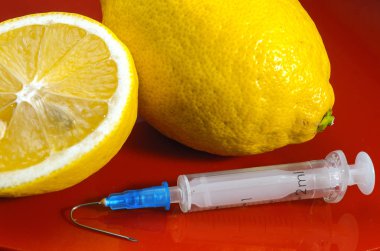 Limon ve şırınga kırmızı bir arka plan üzerinde. Vitamin ilaçları karşı. C vitamini.