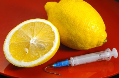 Limon ve şırınga kırmızı bir arka plan üzerinde. Vitamin ilaçları karşı. C vitamini.