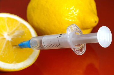 Limon ve şırınga kırmızı bir arka plan üzerinde. Vitamin ilaçları karşı. C vitamini.