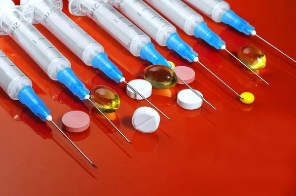 Syringe. Pills. Syringes with tablets on a red background. Injectors with medical preparations — Stock Photo, Image