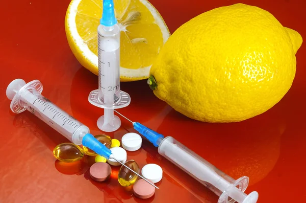 Limoni e Siringa su sfondo rosso. Vitamine contro i farmaci. Vitamina C . — Foto Stock