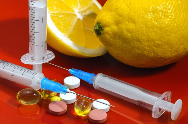 Limon ve şırınga kırmızı bir arka plan üzerinde. Vitamin ilaçları karşı. C vitamini.