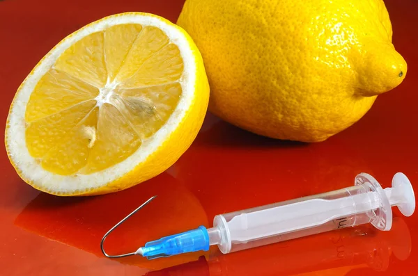 Limoni e Siringa su sfondo rosso. Vitamine contro i farmaci. Vitamina C . — Foto Stock