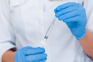 Bir doktorun elinde yüz gerdirme ameliyatı için enjeksiyonu olan bir şırınganın yakın çekimi..