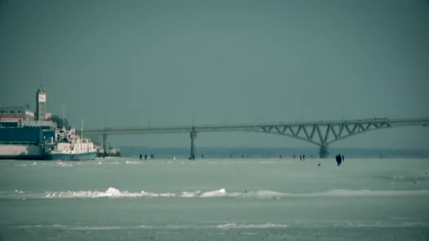 Mensen lopen op ijs onder de brug — Stockvideo