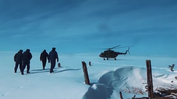 La gente camina hacia el helicóptero en la nieve — Vídeo de stock