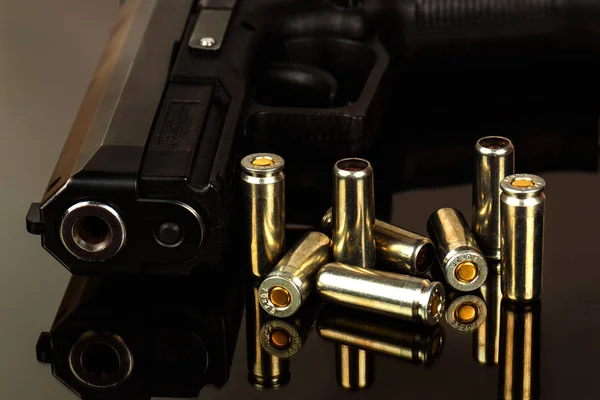 De zwarte pistool en cartridges aan hem op een zwarte achtergrond — Stockfoto