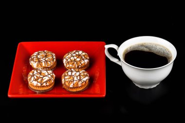 Kırmızı bir tabak içinde kahve ve çikolata soslu kurabiyeleri fincan