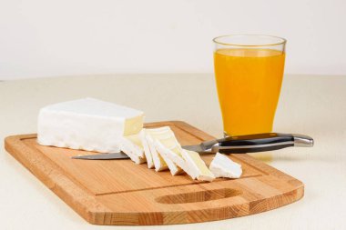 Peynir bir ahşap kesme tahtası ve bir bardak portakal suyu da kahvaltıda dilimlenmiş.