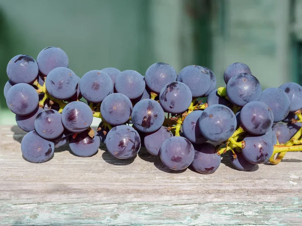 Eine zerrissene Traube roter Trauben liegt auf einem alten Brett. — Stockfoto