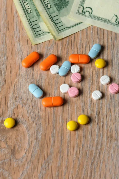 Assorted colored pills and money on the table. The concept of buying pills. The concept of increasing the price of tablets.