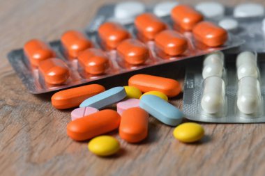 Masanın üzerinde çeşitli renkli tabletler ve tablet ambalajlar var. Koronavirüs enfeksiyonunun korunma ve tedavisi kavramı.