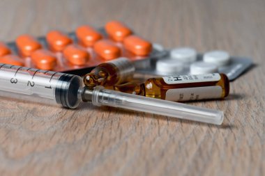 Şırınga, ampul ve haplar masaya yakın çekim. Koronavirüs enfeksiyonuna karşı aşı kavramı.