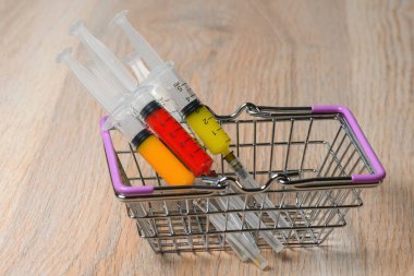 Bir covid virüs enfeksiyon ilacı aşısı satın alma fikri. Sepette renkli şırıngalar.