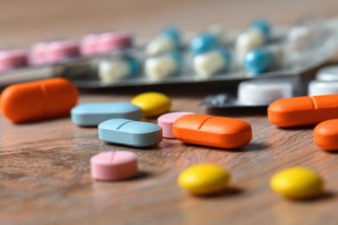 Masanın üzerinde çeşitli renkli tabletler ve tablet ambalajlar var. Koronavirüs enfeksiyonunun korunma ve tedavisi kavramı.