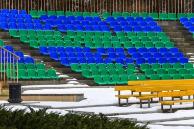 Kışın karda seyirci koltukları. Bir kış parkında bir amfi tiyatronun boş koltukları..