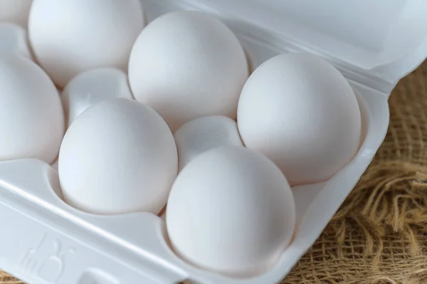 White raw chicken eggs in a plastic tray close-up. Chicken eggs background.