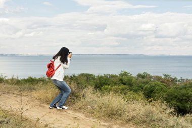 Kot pantolon ile a fotoğraf makinesi kırmızı bir sırt çantası ile genç kız (esmer)